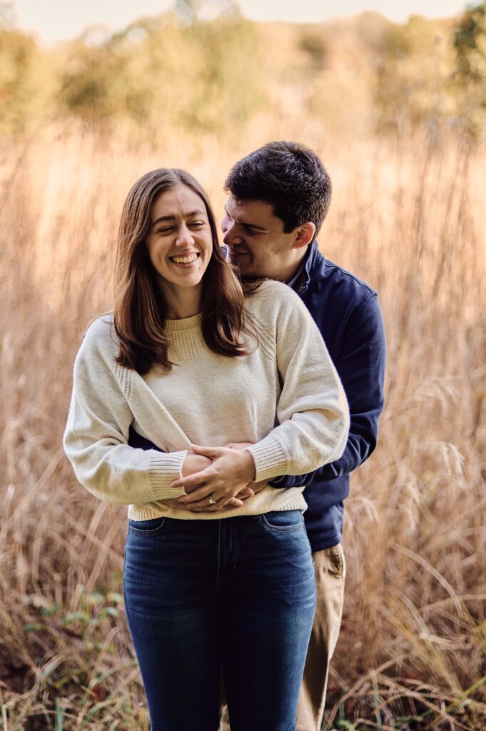 Couple cuddling up in the middle of a field at the Nichols Arboretum in Ann Arbor, Michigan