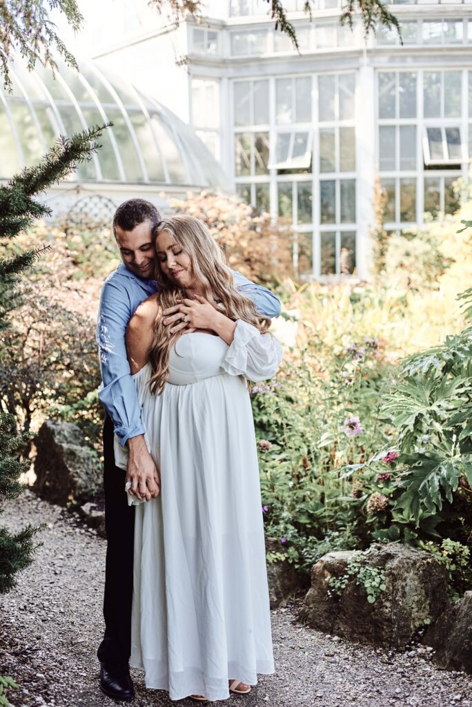 engagement couple embrace in an outdoor garden at the Anna Scripps Conservatory on Belle Isle in Detroit, Michigan