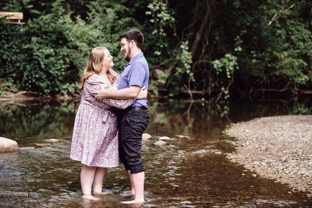 Engagement couple standing in the creek holding each other at the Rochester Municipal Park in Downtown Rochester, Michigan. One of the perfect Metro Detroit engagement session locations. Taken by Erika Black Photography
