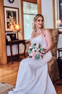 Bride posed on chair holding her pink and green bouquet at Wellers in Saline, Michigan. Photo taken by