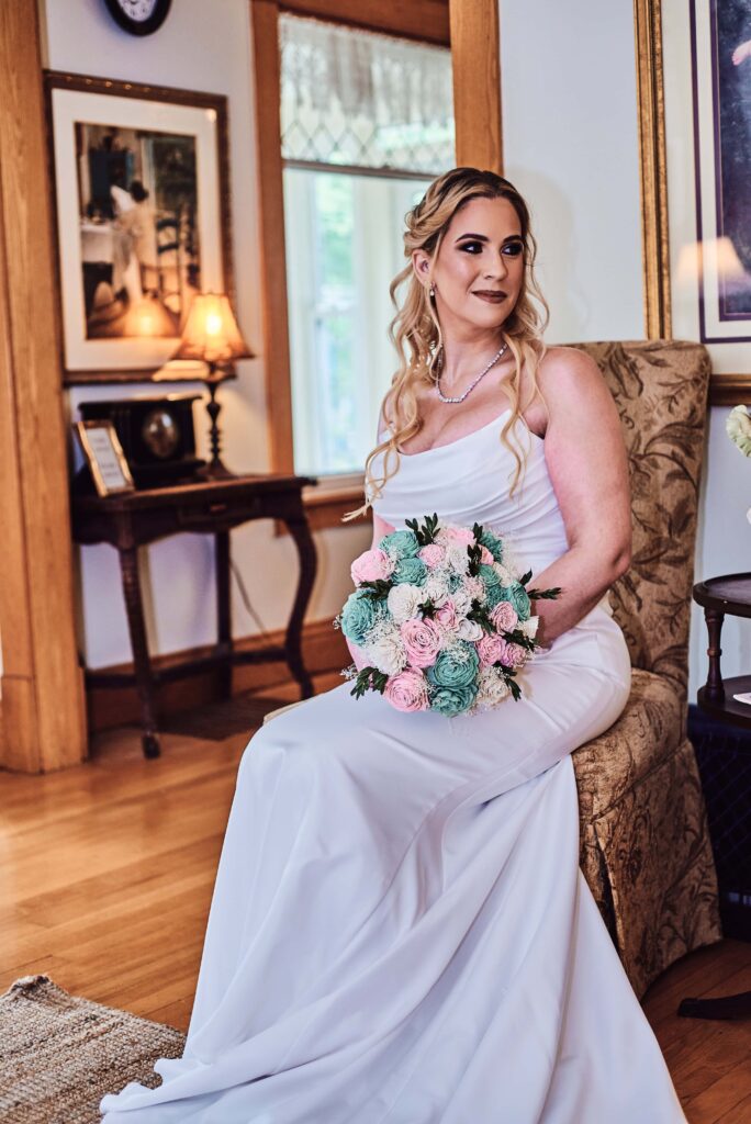 Bride posed on chair holding her pink and green bouque