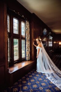 Bride leaning against wood frame of window looking outside at the Detroit Country Club in Grosse Pointe, Michigan