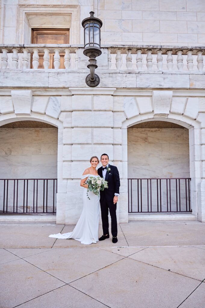 Bride and groom stand outside the white marble walls and arches of the Detroit Institute of Arts in Detroit, Michigan