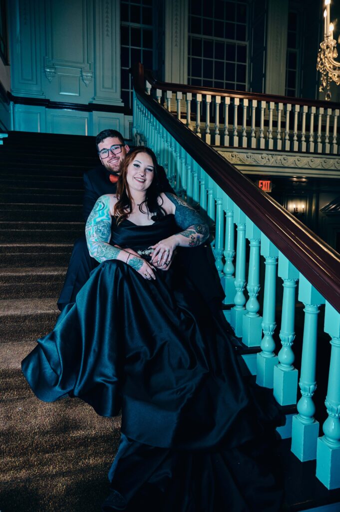 A bride sits back into the groom while they sit together on the staircase at the Henry Ford Museum