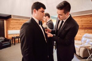 groomsman pinning boutonniere to groom in the groom's room at Pine Knob Mansion