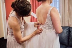 Maid of Honor helps bride with her dress at Silver Shores wedding venue in Wyandotte, Michigan