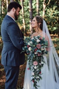 Bride and groom look at each other in woods at Sunset Hill Wedding Barn