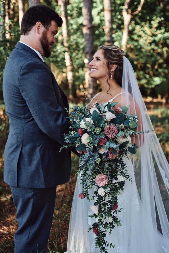 Bride and groom look at each other in woods at Sunset Hill Wedding Barn
