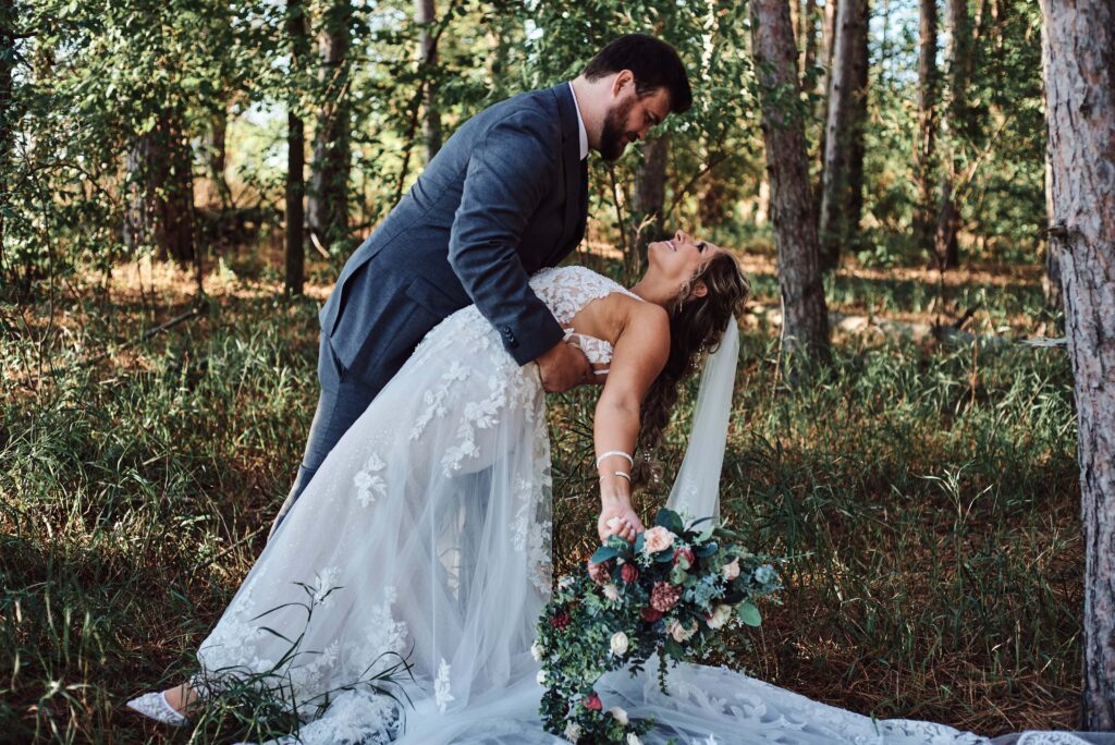 Groom dips bride in woods at Sunset Hill Wedding Barn