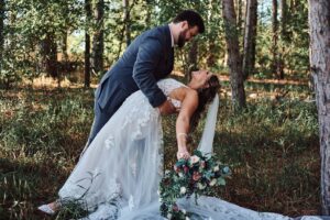 Groom dips bride in woods at Sunset Hill Wedding Barn