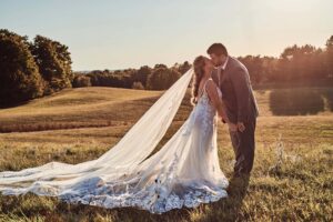 Bride and groom kiss at sunset at Sunset Hill Wedding Barn