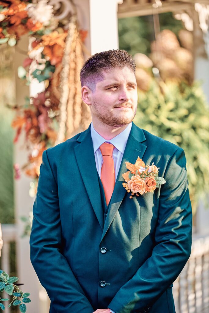 The groom looks on as he starts to see the bride walk down the aisle at Lapeer Country Club