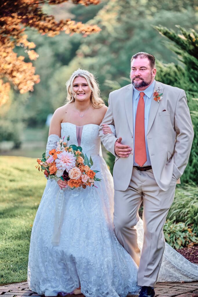 The bride and her father walk together down the aisle at Lapeer Country Club