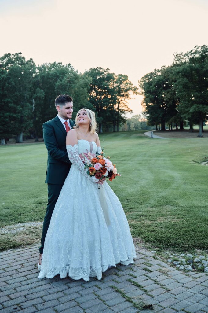 The groom and bride snuggle each other at sunset at Lapeer Country Club