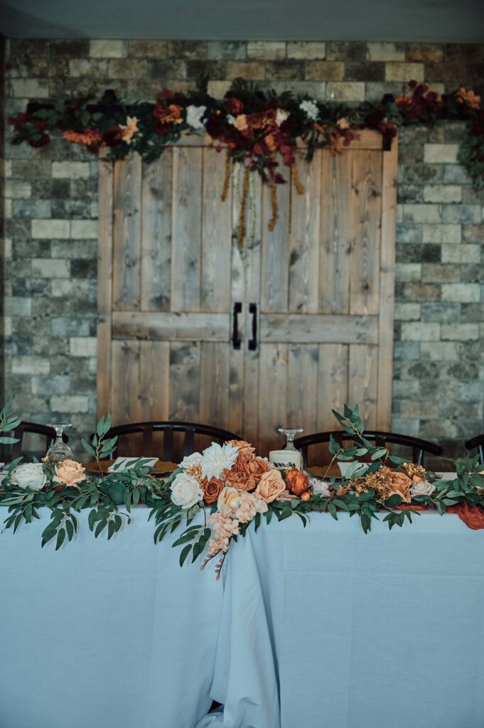 Wedding party head table in front of Lapeer Country Club barn door display.