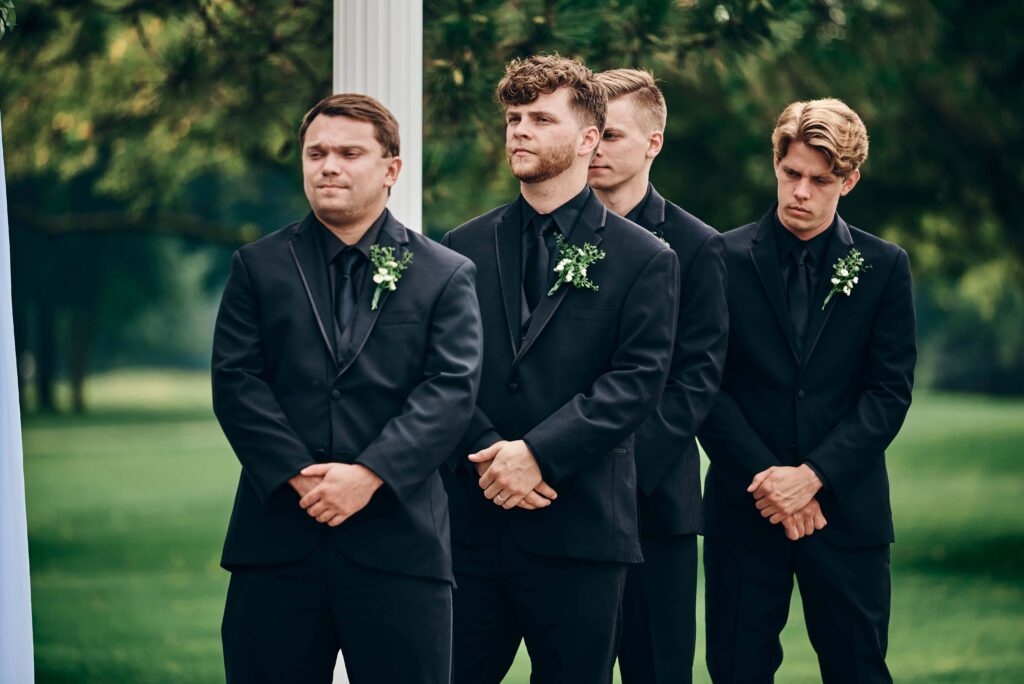 Groomsmen look on as the groom says his vows during the ceremony