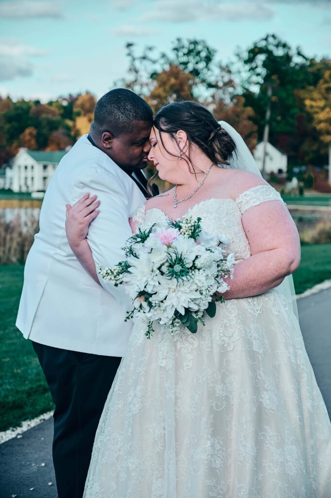 A bride and groom nuzzle together and holding each other with their faces close to each other